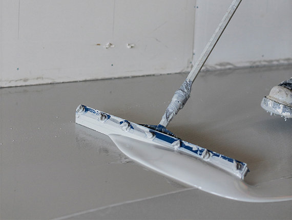 Worker finishing a concrete floor to prepare it for polyurethane coating